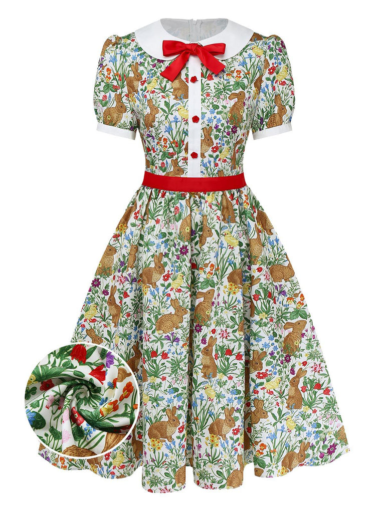 Ein kurzärmeliges A-Linien-Kleid im Vintage-Stil mit verspieltem Hasen- und Wildblumenmuster, weißem Peter-Pan-Kragen und roter Schleife als Akzent.
