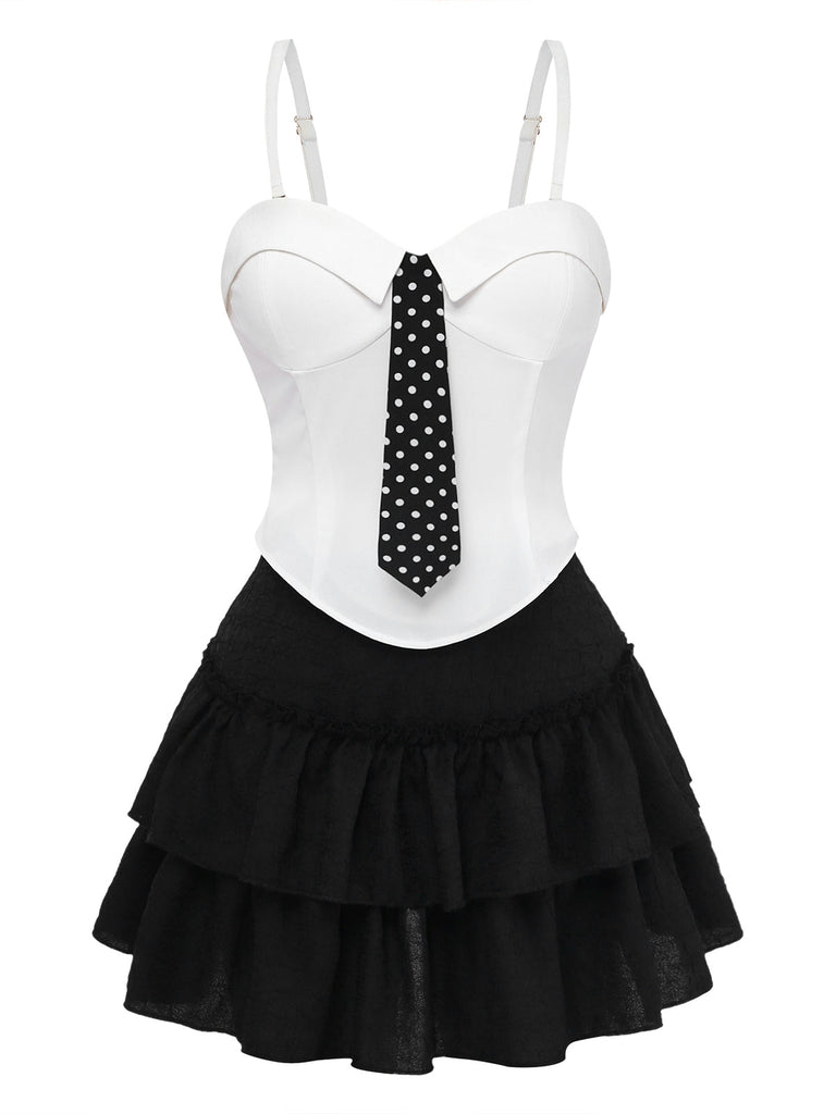 Weißes Oberteil mit schwarzer gepunkteter Krawatte und schwarzem Rüschenrock auf weißem Hintergrund