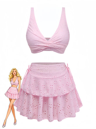 Pinkes Bikini-Oberteil und Rock mit einer Puppe, die das Outfit trägt, vor weißem Hintergrund