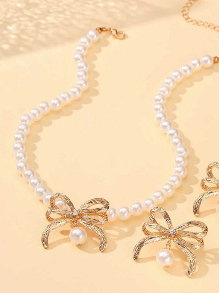 Perlenkette mit goldenen Schleifenanhängern auf gelbem Hintergrund