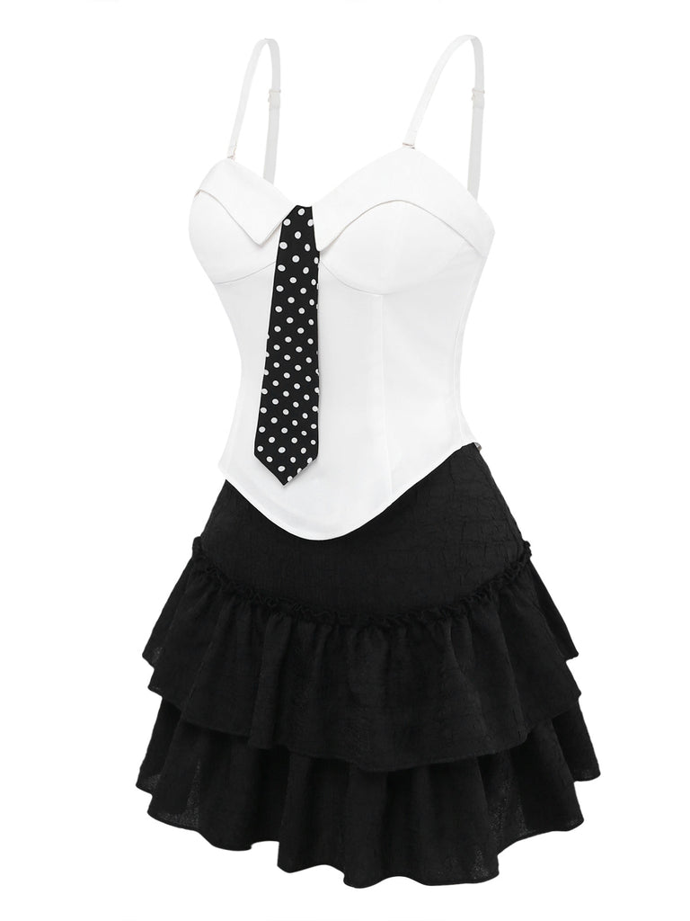 Weißes Oberteil mit schwarzer gepunkteter Krawatte und schwarzem Rüschenrock auf weißem Hintergrund