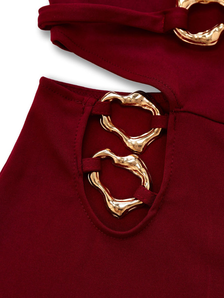 Nahaufnahme eines bordeauxroten Kleides mit goldenen Gürteldetails vor weißem Hintergrund