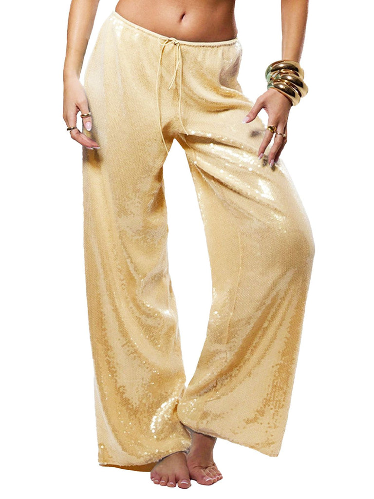 Eine Person trägt eine goldene Paillettenhose vor einem weißen Hintergrund.