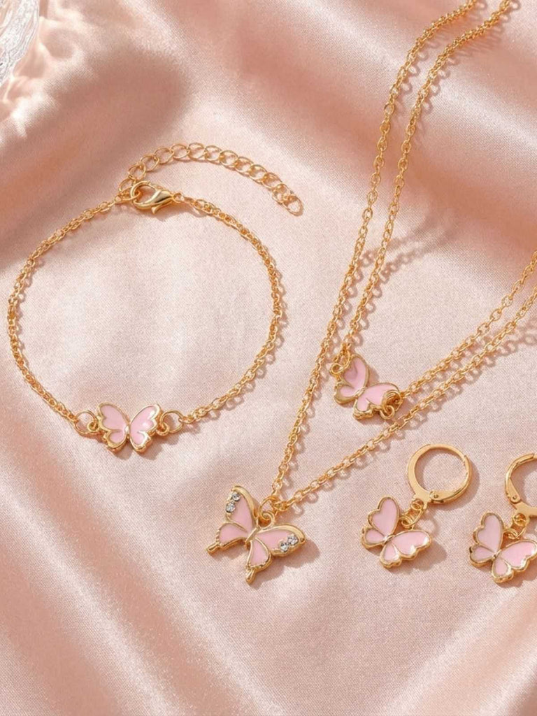 Goldfarbenes Schmuckset mit rosa Schmetterlingsanhängern auf rosa Stoffhintergrund