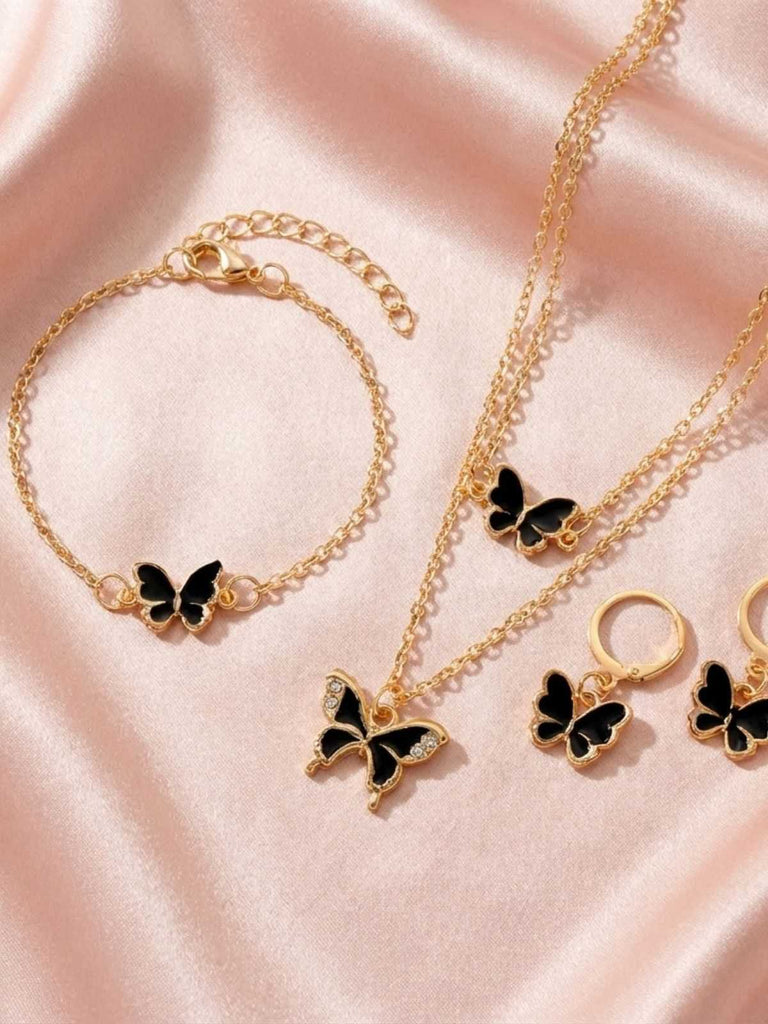 Goldfarbenes Schmuckset mit Schmetterlingsanhängern auf rosa Satin-Hintergrund