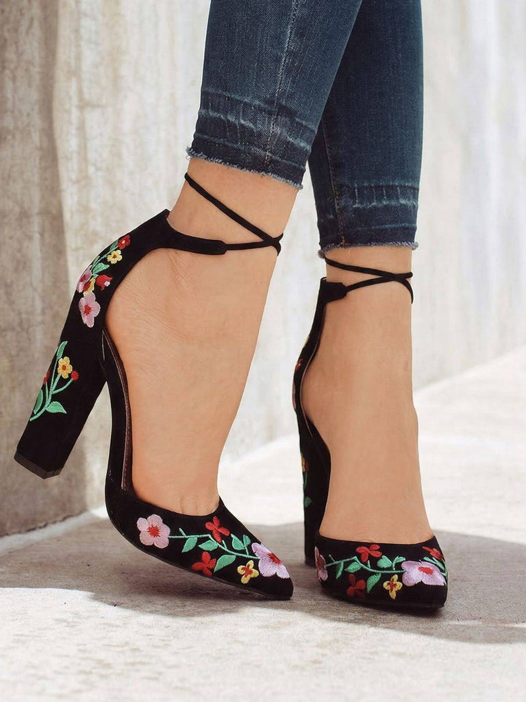 Schwarze High Heels mit Blumenstickerei, getragen zu hochgekrempelten Jeans.