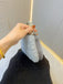 Hand hält eine silberne Perlenclutch vor neutralem Hintergrund