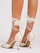 Beigefarbene High Heels mit Zierbändern auf weißem Hintergrund