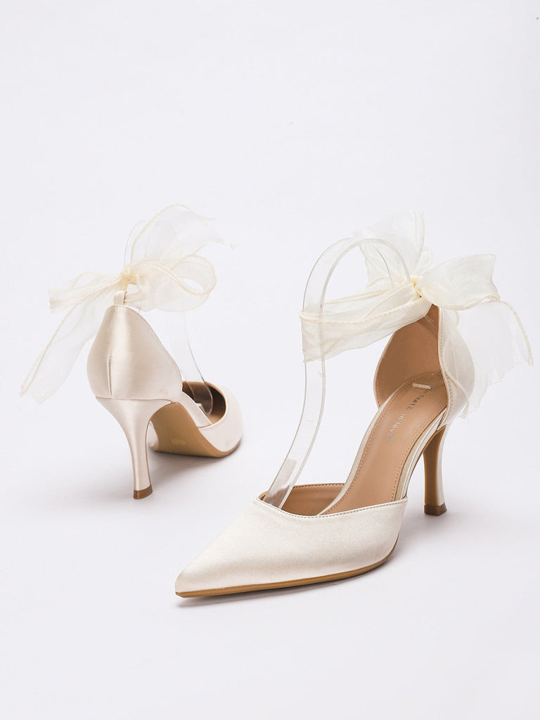 Beigefarbene High Heels mit transparenten Riemen und Bändern auf weißem Hintergrund