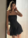 Ein Model posiert in einem schwarzen, gepunkteten Badekleid vor einem neutralen Innenraumhintergrund.