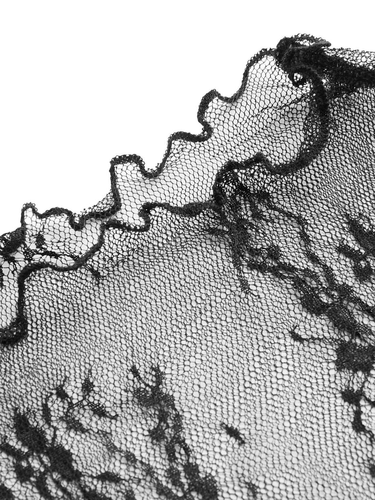 Nahaufnahme des zarten, transparenten Spitzenstoffs mit Blumenmuster und der gewellten Kante des langärmeligen Oberteils.