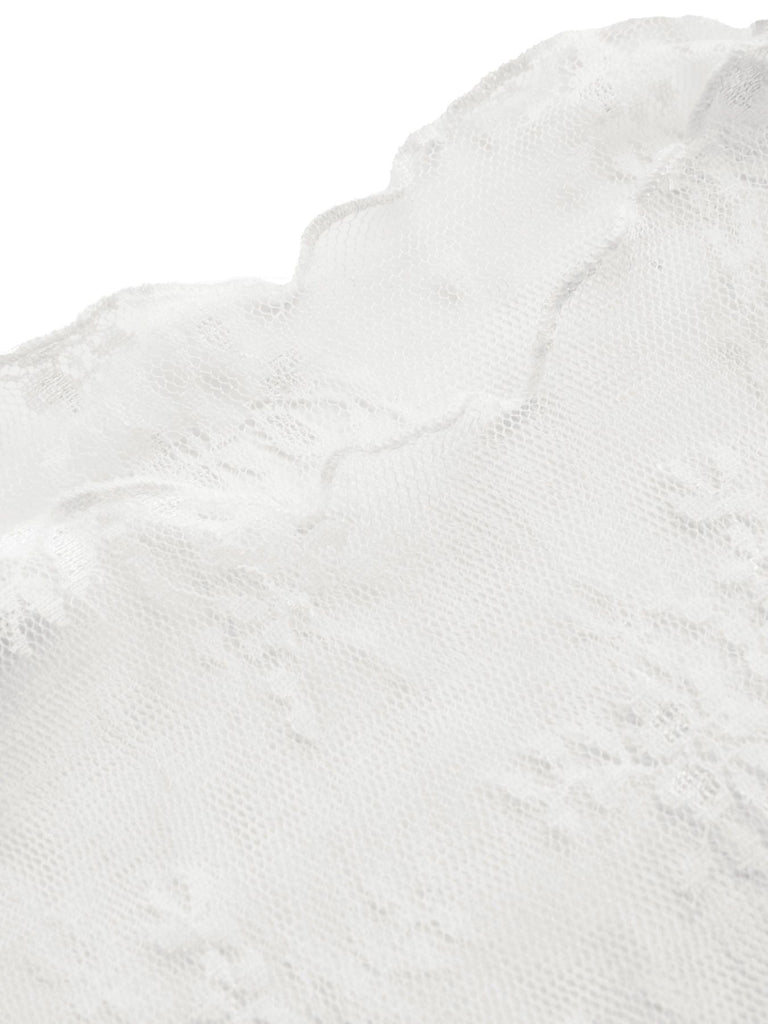 Detailansicht des weißen, langärmeligen Oberteils aus floraler Spitze, kombiniert mit einem schwarzen Jumpsuit.